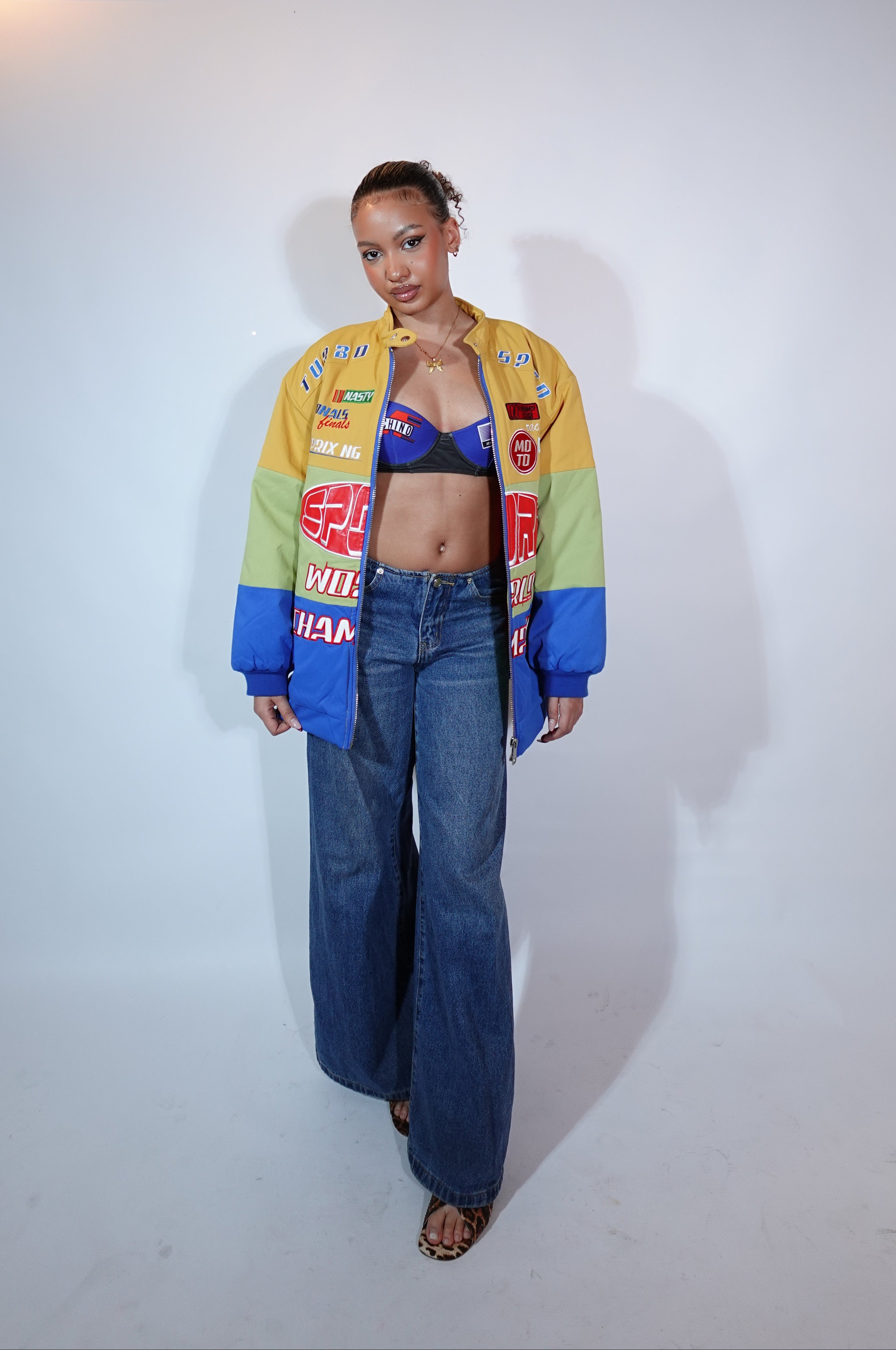 Person wearing a colorful jacket and blue jeans on a white background